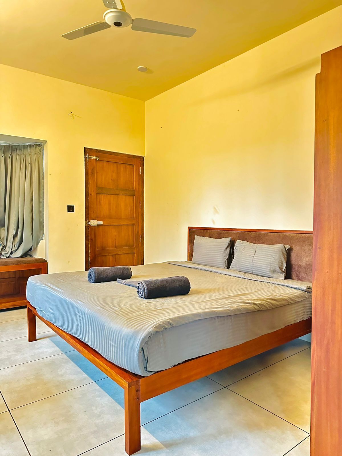 A bedroom with a wooden bed, two pillows, a ceiling fan, and a wooden door.