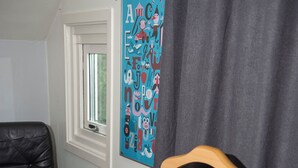 Ein Zimmer mit einem schwarzen Ledersessel, einem hölzernen Stuhl mit Metallbeinen, einem kleinen Tisch und einem farbenfrohen abstrakten Gemälde an der Wand.