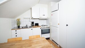 Eine kleine Küche mit weißen Schränken, einem Herd und einem Kühlschrank.