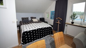 Ein Schlafzimmer mit Bett, zwei Stühlen, einem Fenster und einer Heizung.