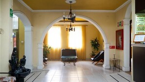 A hotel lobby with a central seating area, a chandelier, and a fountain. - Hotel Plaza CA (Merida)