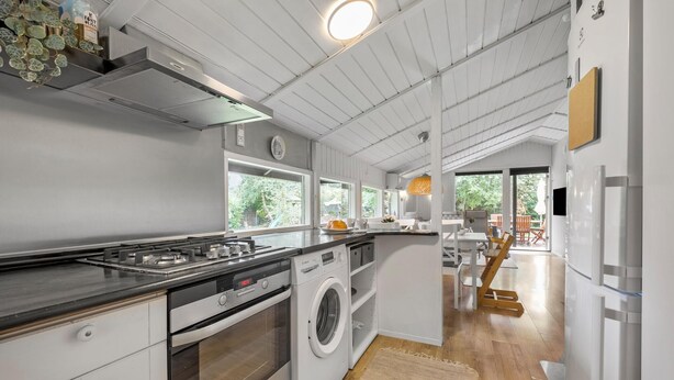 Une cuisine moderne équipée d’une cuisinière à gaz, d’un four et d’un lave-linge encastré.