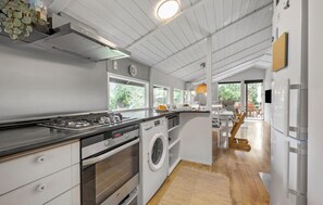 A modern kitchen with a gas stove, oven, and built-in washing machine.