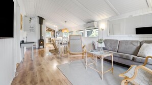 Un vaste espace de vie doté d’un plancher en bois, d’un canapé, de deux fauteuils, d’une table et d’une cheminée.
