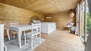 Une cabane en bois avec une chambre à coucher située en mezzanine, un coin repas et un salon offrant une vue panoramique.