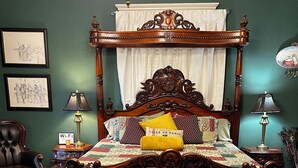 Un lit traditionnel à baldaquin, avec un banc au pied du lit et un tapis à motifs.