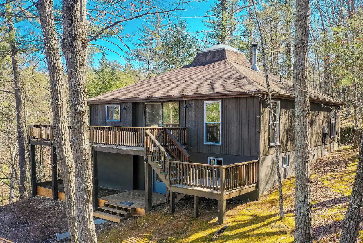 A cabin with a deck, a chimney, and a small porch.