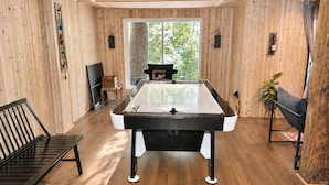 Une table de billard dans une pièce aux murs en bois et dotée d’une grande fenêtre.