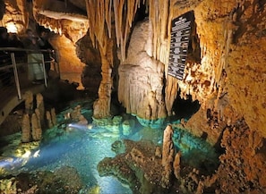 A cave with stalactites and stalagmites, a pool of water, and a sign with text. - CasaSOL: Stylish Mountain Cabin with Game Room, Trails and Fire Pit Nights (Basye)