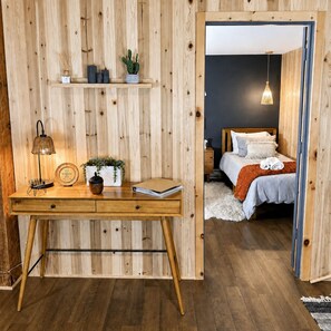 A wooden room with a desk, a bed, and a hanging light fixture.