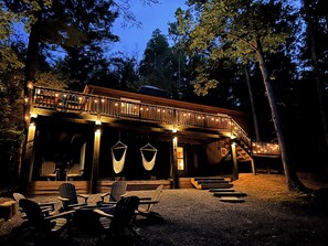 A wooden cabin with a covered porch, outdoor seating, and hanging hammocks. - CasaSOL: Stylish Mountain Cabin with Game Room, Trails and Fire Pit Nights (Basye)