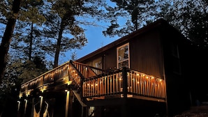 Une cabane en bois dotée d’une terrasse en bois et d’un escalier menant à un porche vitré.