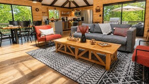 Un vaste espace de vie doté d’un plancher en bois, d’un canapé, d’un fauteuil rouge et d’une table à manger.