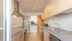 A modern kitchen with stainless steel appliances, wooden cabinets, and a built-in dishwasher.
