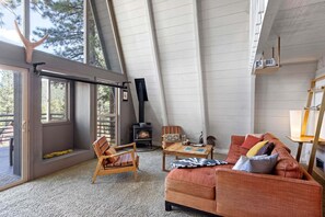Un acogedor salón estilo loft con chimenea, un sofá, un sillón y una mesa.