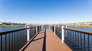 A wooden pier leading to a body of water with a clear sky.