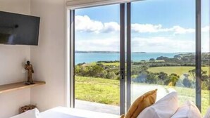Une chambre dotée d’une grande fenêtre offrant une vue panoramique sur un paysage côtier.