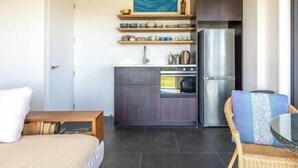 Une cuisine compacte dotée d’appareils électroménagers modernes, un coin repas avec une table et des chaises, et un lit avec vue.