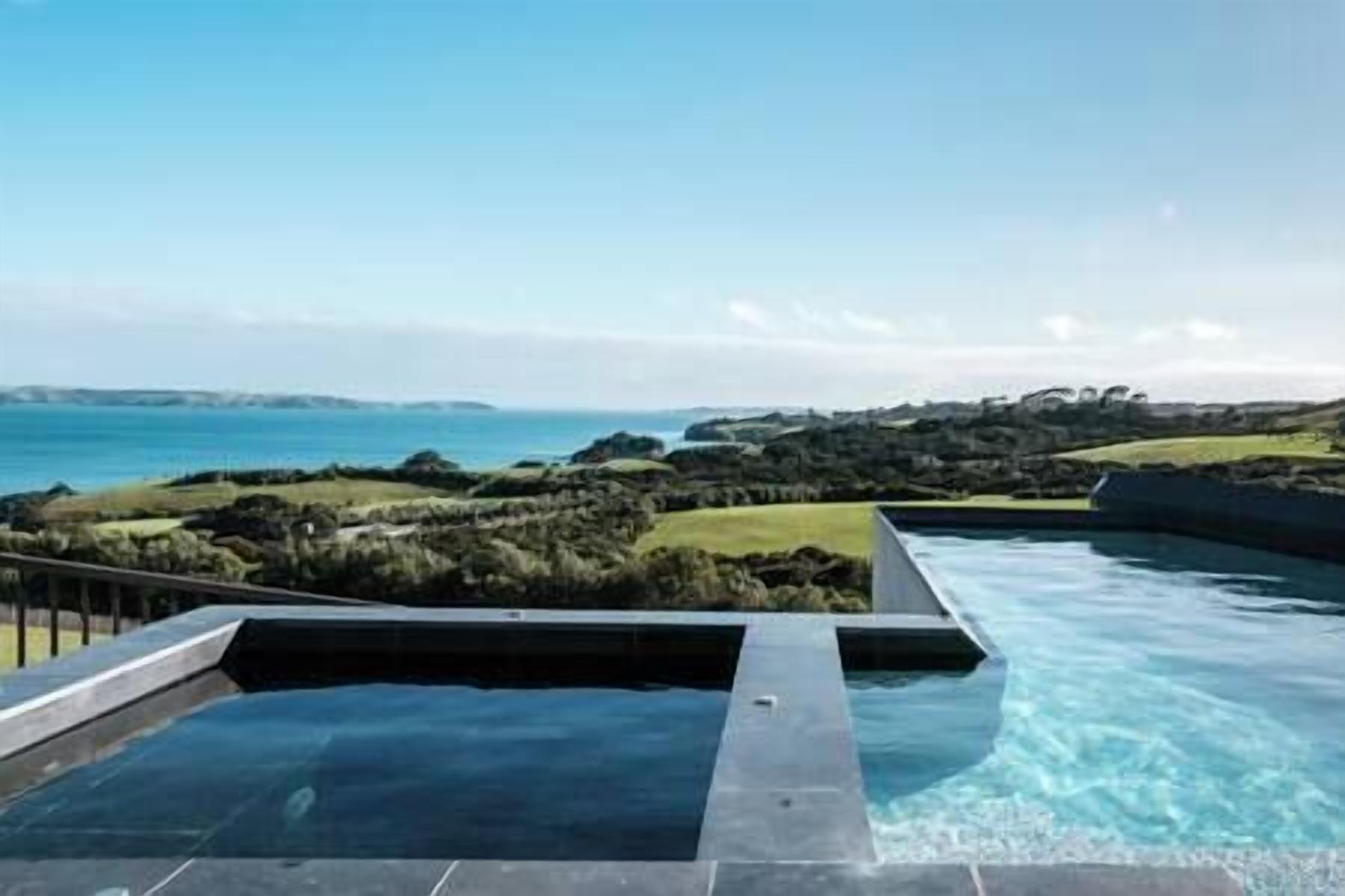 A infinity pool with a clear view of the ocean and distant hills.
