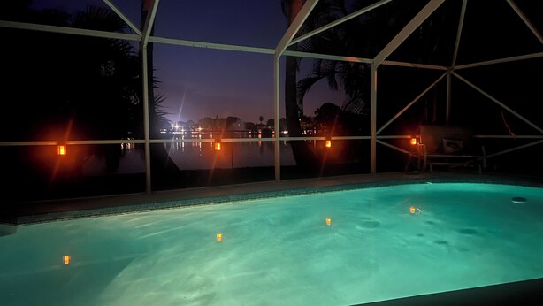 A swimming pool with a view of the night sky and distant city lights.