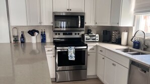 A modern kitchen with white cabinets, stainless steel appliances, and a built-in dishwasher.