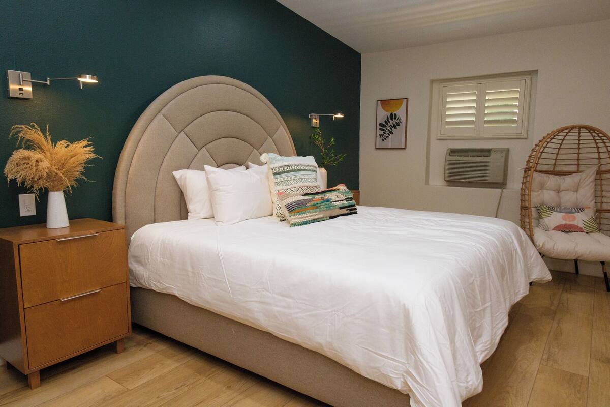 Un dormitorio con cama, mesita de noche, lámpara y adornos.