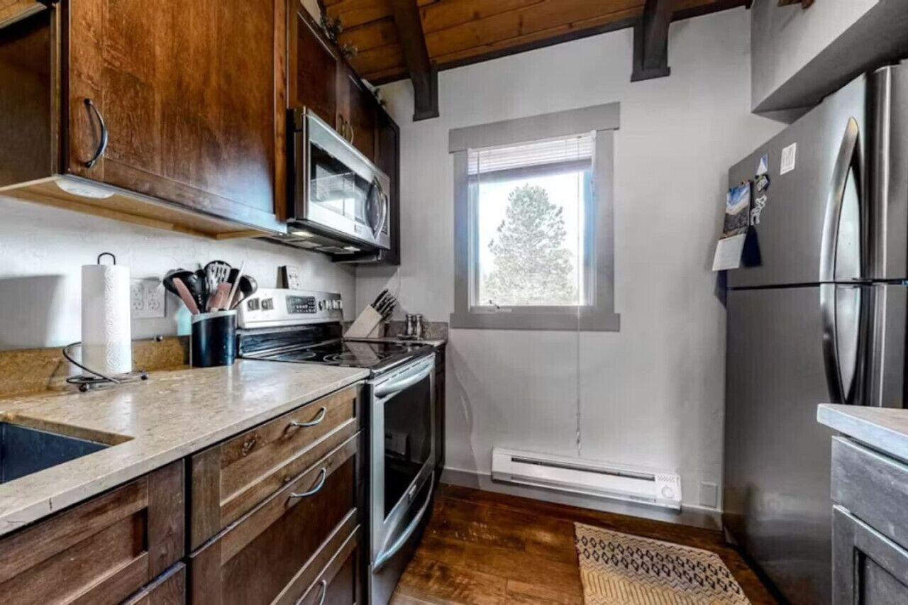 A kitchen with wooden cabinets, a stainless steel refrigerator, and a window providing natural light.