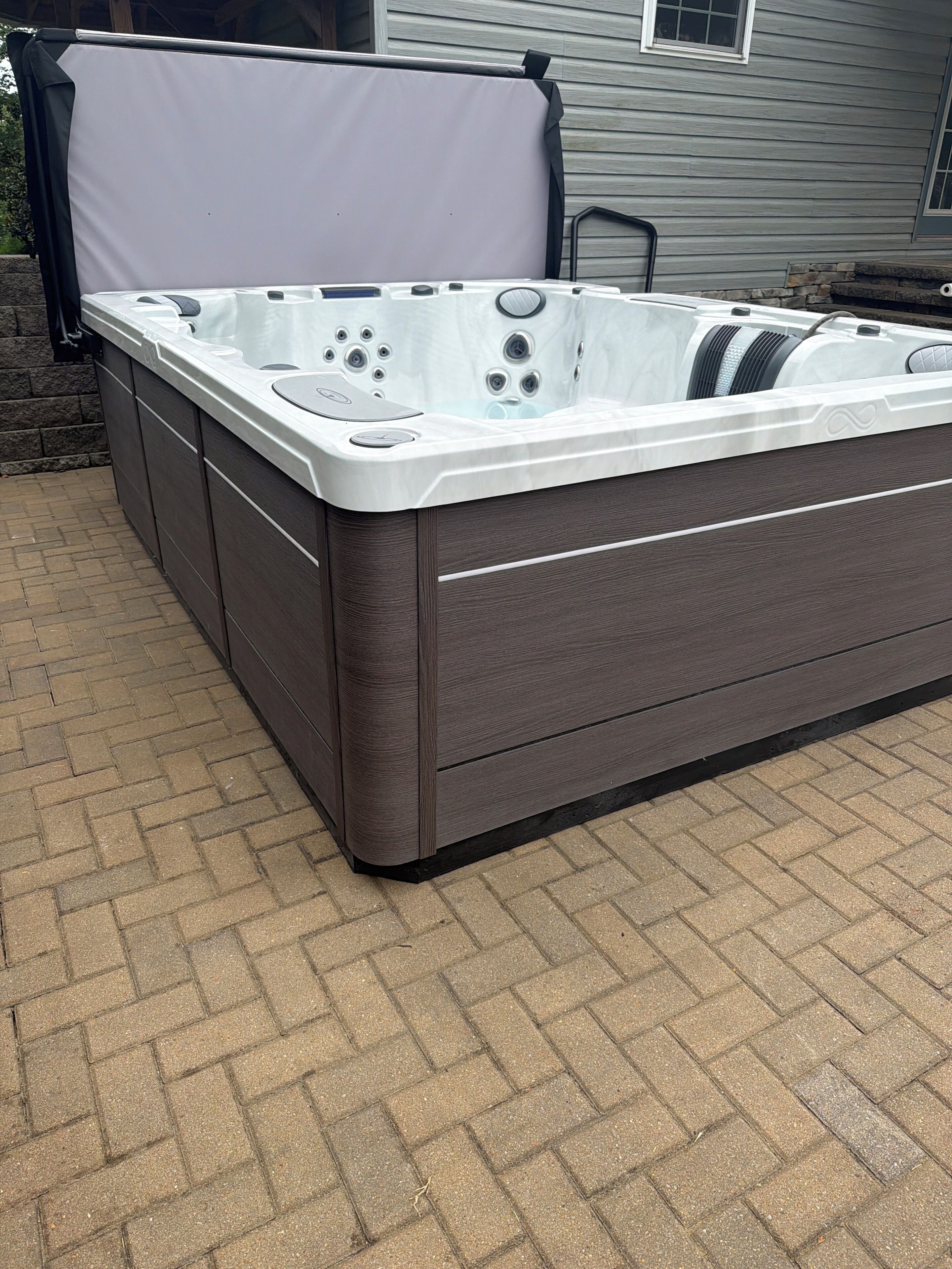 Jacuzzi de spa con tapa, sobre un patio de ladrillo.