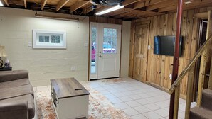 Una habitación con techo de madera, una puerta blanca, un televisor montado en la pared y una pequeña mesa con un control remoto.