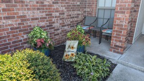 A brick building with a small garden area, a bench, and a chair.