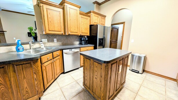 Una cocina con armarios de madera, lavavajillas, refrigerador y pileta.
