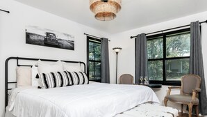 A bedroom with a bed, a chair, a floor lamp, and a window with curtains.