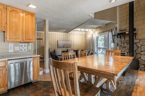 Een ruime keuken met houten kastjes, een RVS vaatwasser en een eethoek met een grote houten tafel en stoelen.