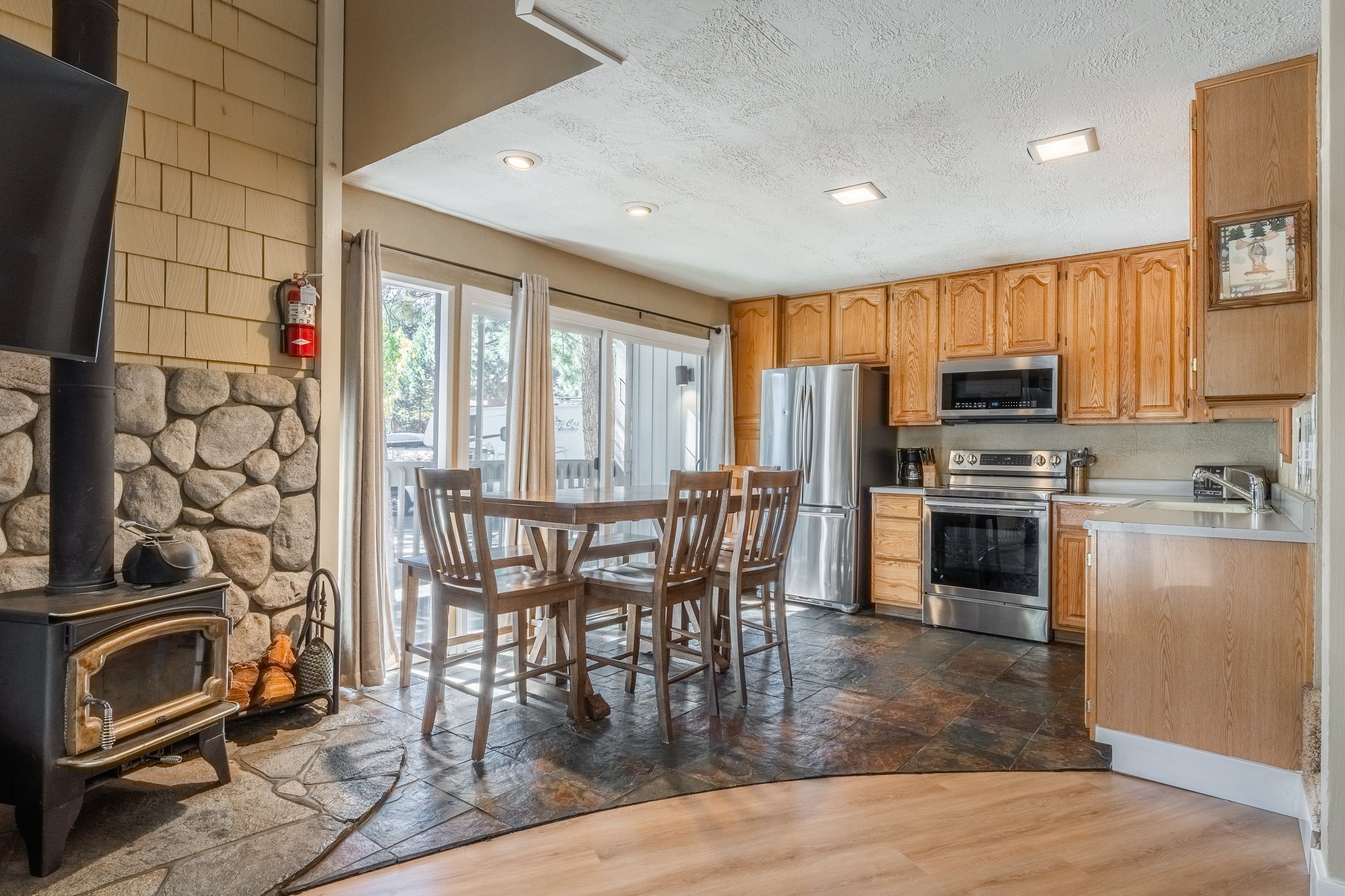A kitchen with a stone wall, wooden cabinets, a built-in oven, and a large dining table.