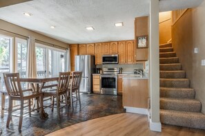 A modern kitchen with wooden cabinets, stainless steel appliances, and a dining area with a table and chairs.
