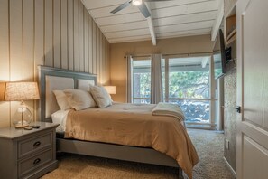 Une chambre à coucher avec un lit, une table de chevet, une lampe et un ventilateur de plafond.