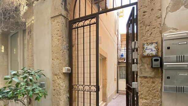 Un callejón estrecho con una reja de hierro forjado, una planta en maceta y el número 40.