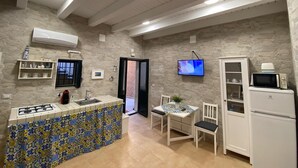 Una cocina compacta con salpicadero de azulejos, estufa integrada, microondas y refrigerador.