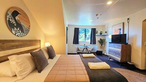 A hotel room with a bed, a desk, a television, and a dining area. - Wild Kea Lodge Franz Josef (Franz Josef Glacier)