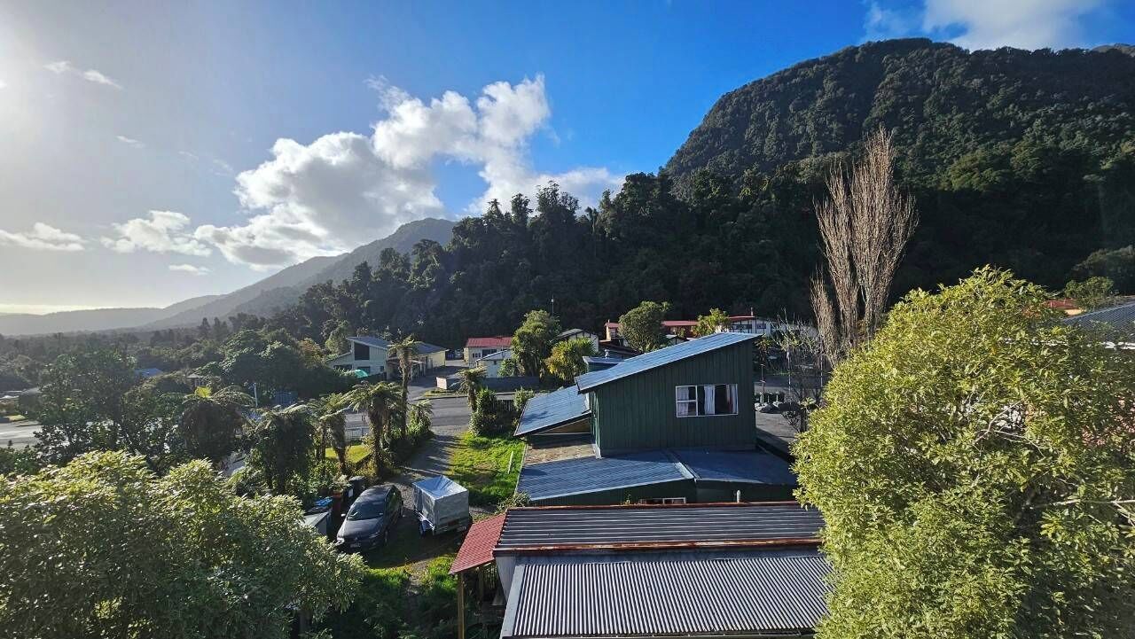 Un barrio residencial con casas, una montaña al fondo y cielo despejado.