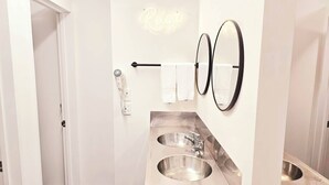 A modern bathroom with a double sink, a towel rack, a hairdryer, and a neon sign. - Wild Kea Lodge Franz Josef (Franz Josef Glacier)