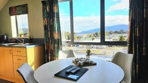 Une pièce comprenant une table à manger, des chaises, un petit coin cuisine et une fenêtre donnant sur un paysage.