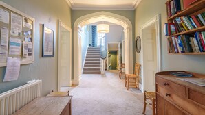 A hallway with a staircase, a wooden desk, and a bookshelf. - Broad How -  Large house ideal for families or walking groups. (Patterdale)
