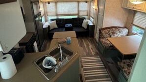 Une cuisine compacte pour camping-car, équipée d’un évier, d’un réfrigérateur et d’un petit coin repas.