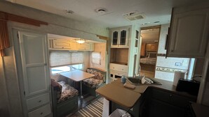 Une cuisine compacte pour camping-car, comprenant un coin repas, un évier et une poubelle.