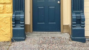 Una porta blu scuro con un piccolo oblò sopra e un cartello che recita 'ROOMS TO LET'.