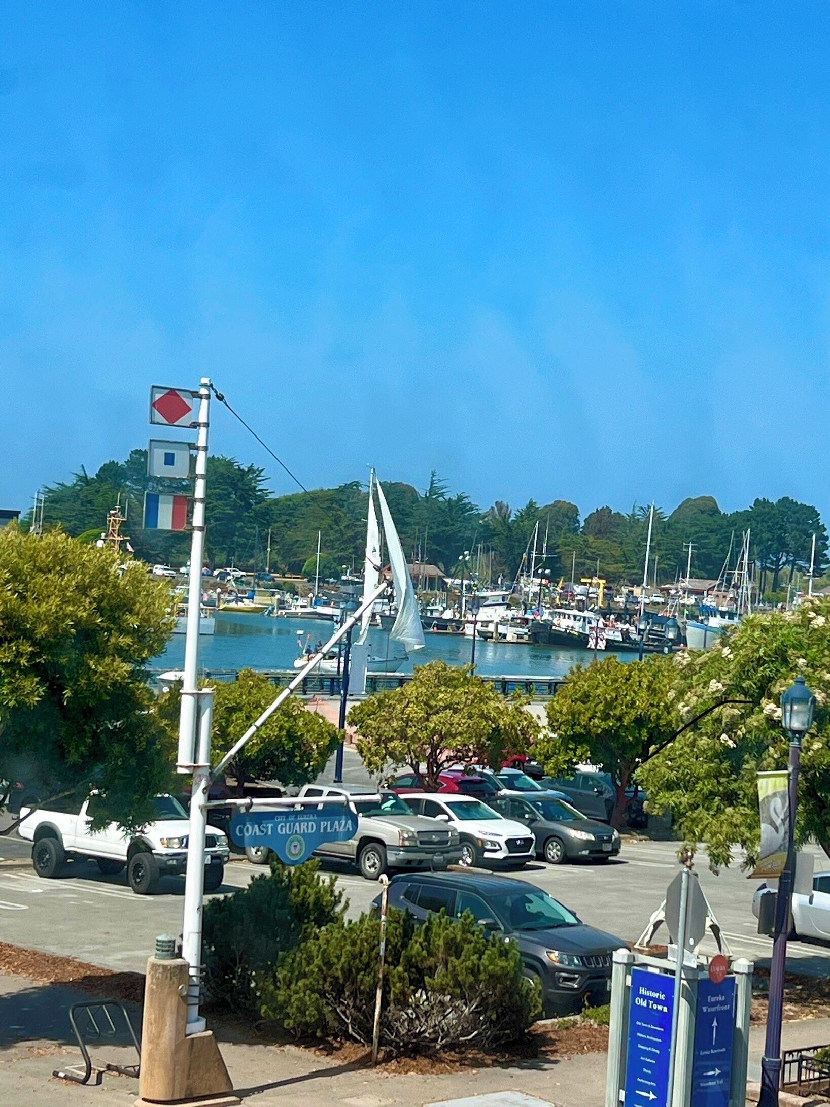Een jachthaven met boten, een zeilboot en een parkeerplaats met auto's.