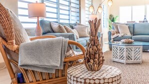 A cozy living room with a wicker chair, a round coffee table, and a blue sofa.