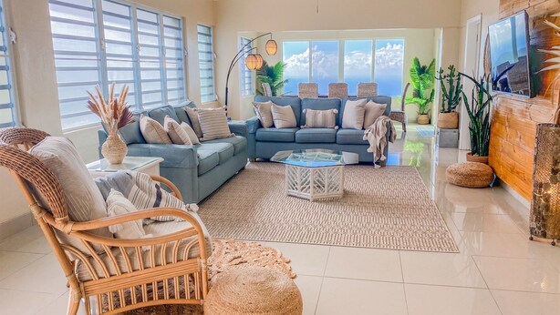 A spacious living room with a blue sofa, wicker chair, and a coffee table.