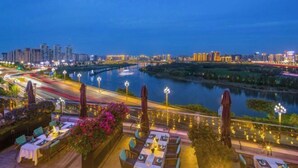 Un restaurante a orillas del río con terraza al aire libre y vistas a un paisaje urbano y al río.